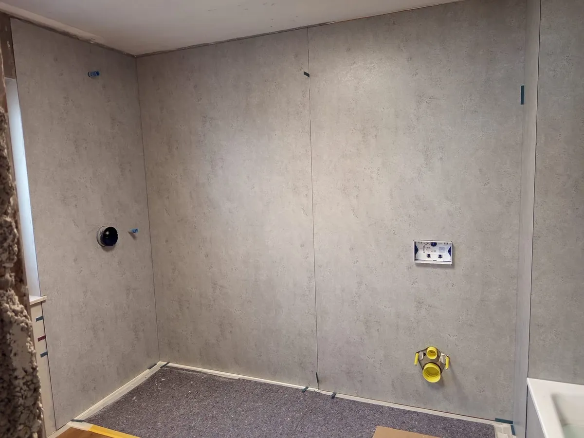 Bad im Umbau: großformatige Wandfliesen in heller Betonoptik und vorbereitete WC-Vorwandinstallation