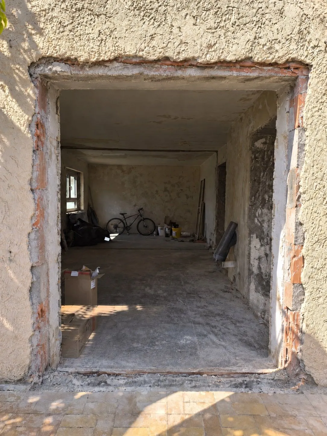 Die Wandöffnung vor der Montage: alte Tür ausgebaut, rohe Laibung, dahinter der Innenraum im Umbau
