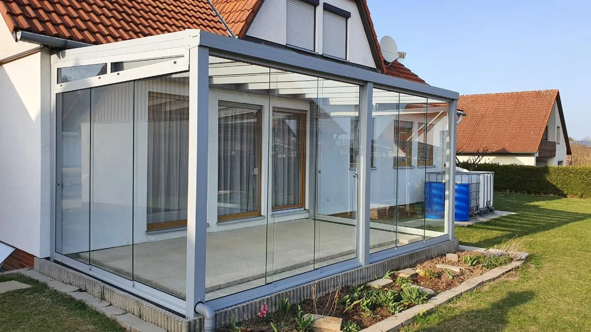 Kaltwintergarten mit weißem Aluminiumrahmen und Glas-Schiebewänden an einer Terrasse
